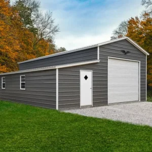 A gray 26X40X12/7 Vertical Roof Metal Garage With 10' Lean-To with a garage door in the middle of a field.