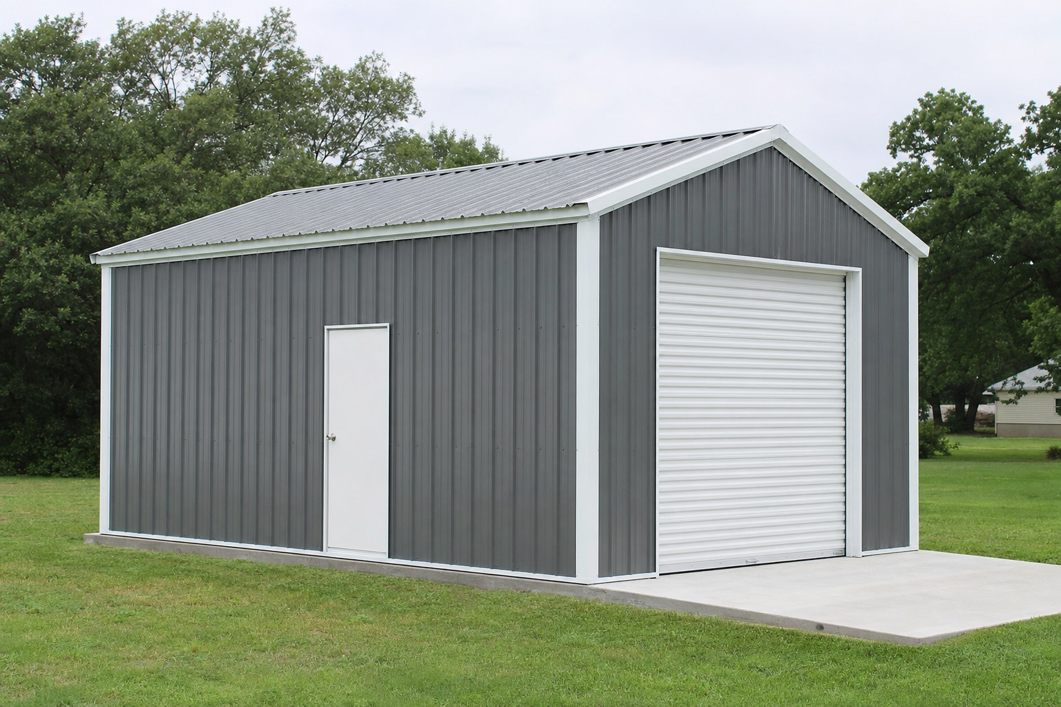 Gray metal garage building with white roll-up door on grass
