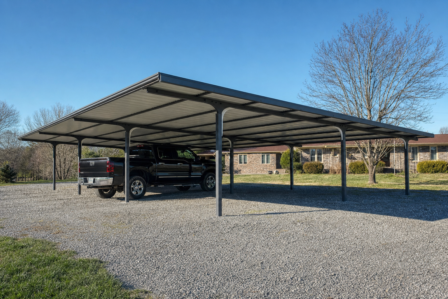 Large metal carport sheltering black pickup truck on gravel
