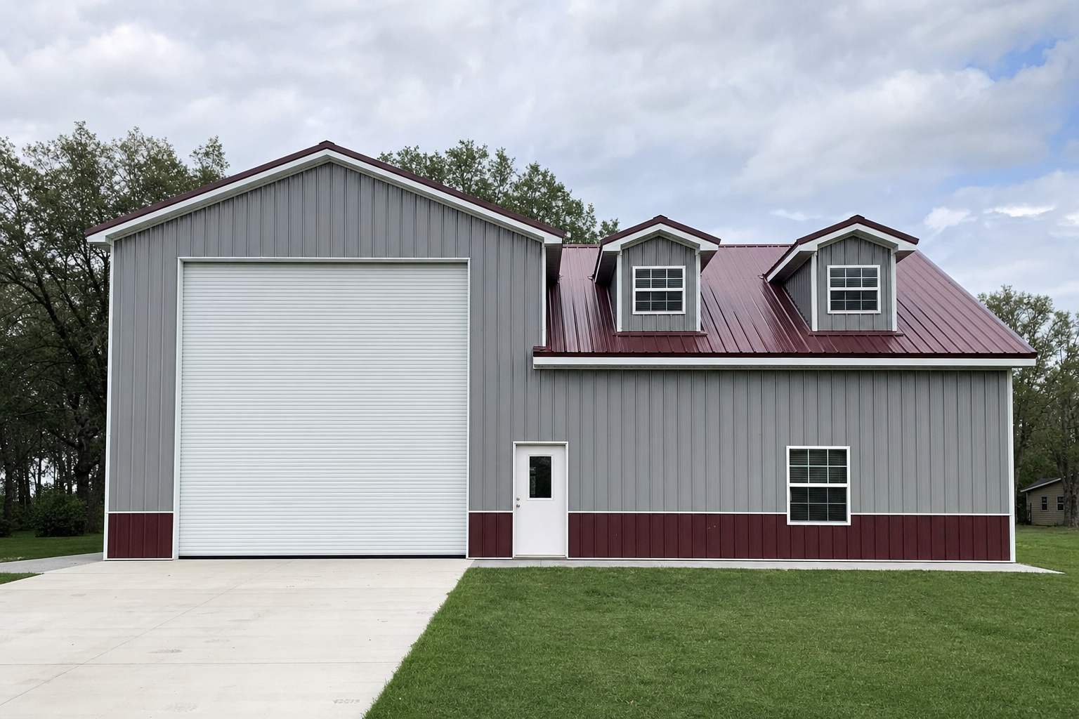 Large gray and red metal pole barn with dormer windows